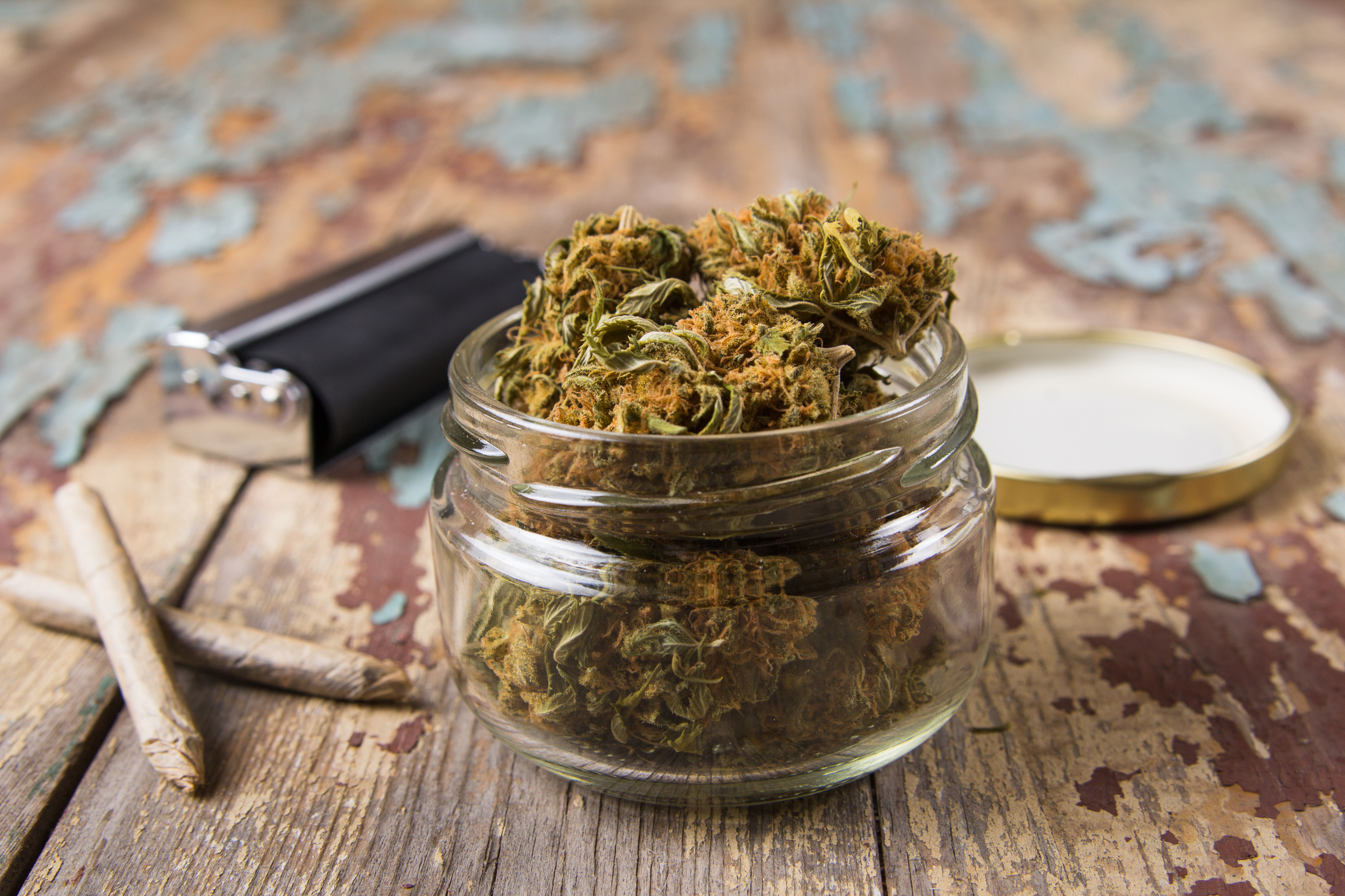 Marijuana buds in the glass pot on the rustic wooden table